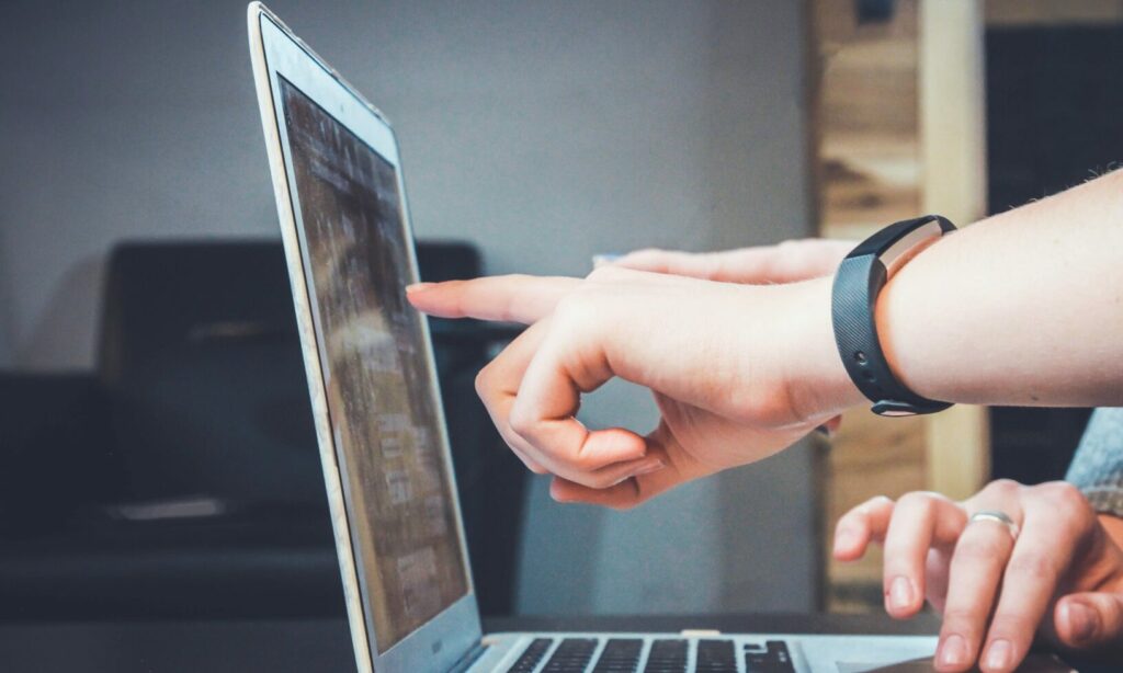 Decorative - pair of hands pointing at laptop screen