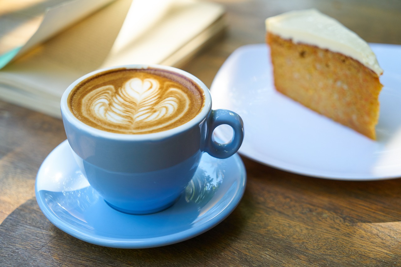 Blue cup of coffee next to a slice of cake.