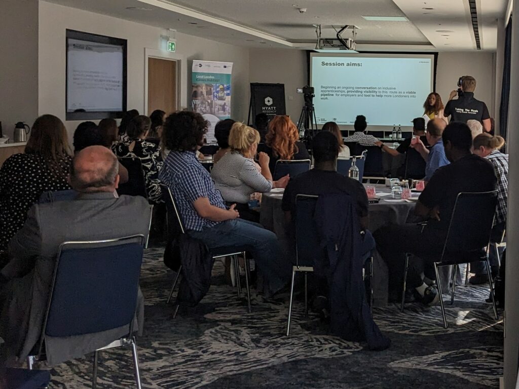 Photo of packed room listening to a speaker at the front