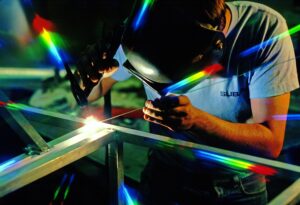 Person wearing protective goggles using tools to manufacture something with metal