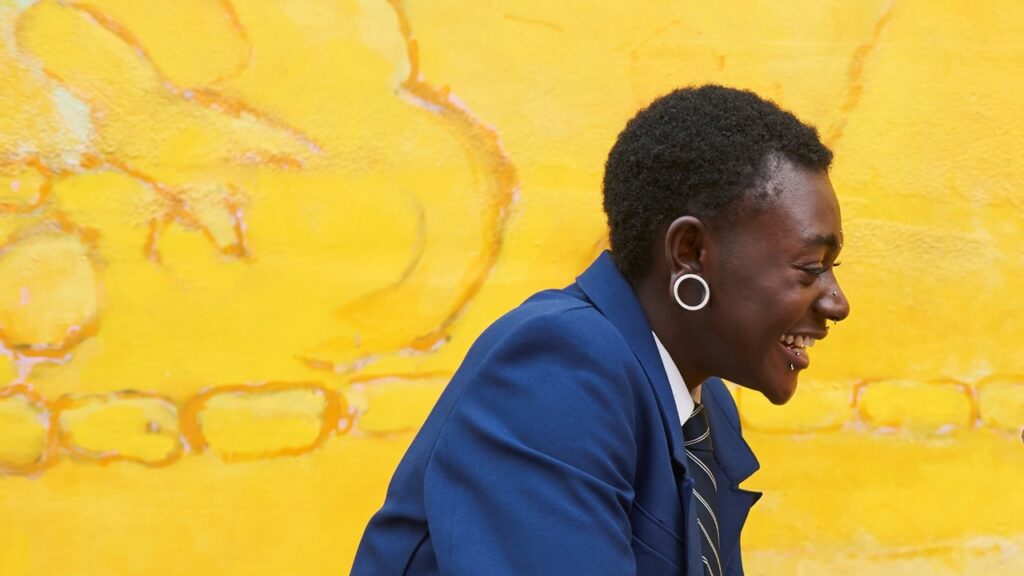 Person smiling against a yellow background