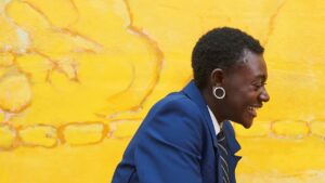 Person smiling against a yellow background 