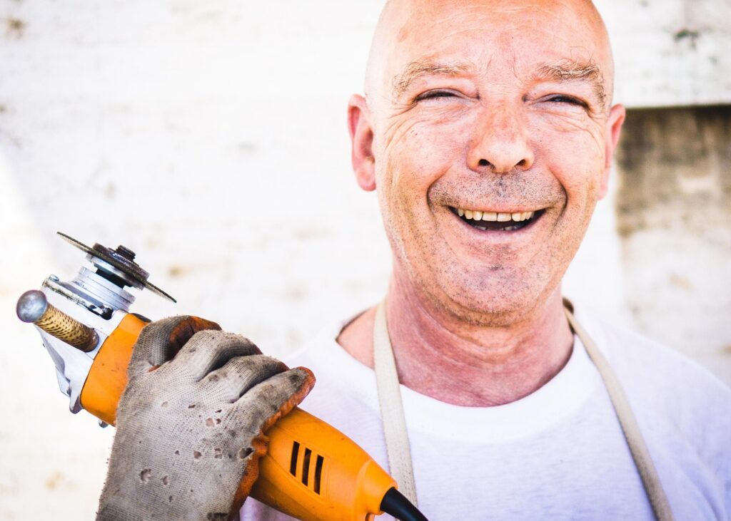 Man smiling holding a hand tool.